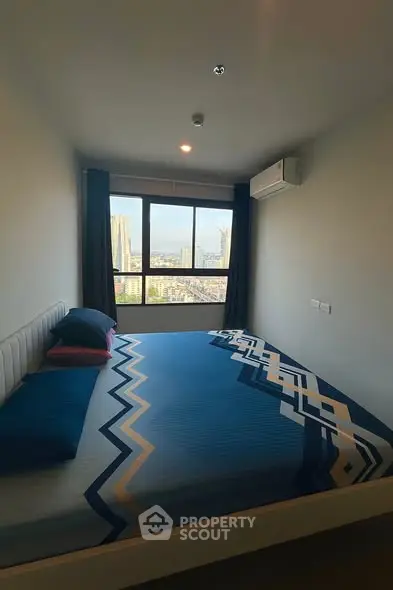 Modern bedroom with large window offering stunning city view, featuring stylish bedding and air conditioning.