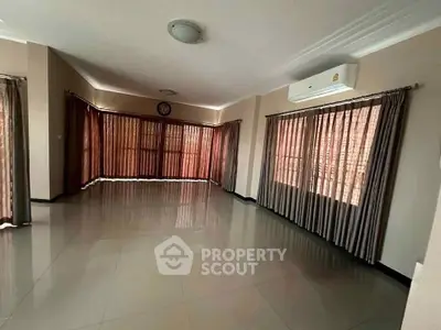 Spacious empty living room with large windows and air conditioning unit.