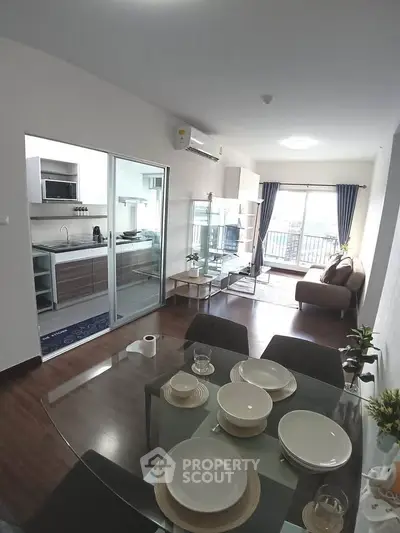 Modern open-plan living room with dining area and kitchen, featuring sleek furniture and a bright, airy atmosphere.