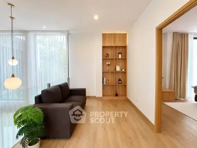 Modern living room with wooden flooring, cozy sofa, and elegant shelving unit.