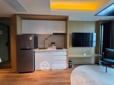 Modern living room with sleek kitchen and wall-mounted TV in stylish apartment.