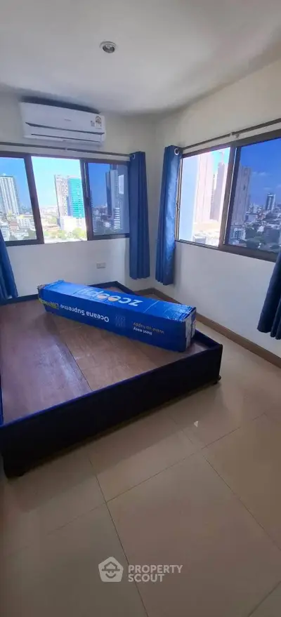 Bright bedroom with large windows offering stunning city views and air conditioning unit.