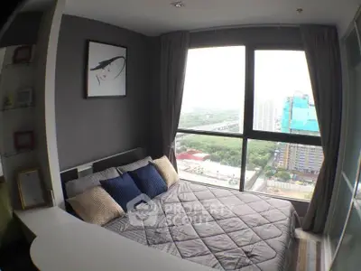 Modern bedroom with large window offering stunning city view, featuring cozy bedding and stylish decor.