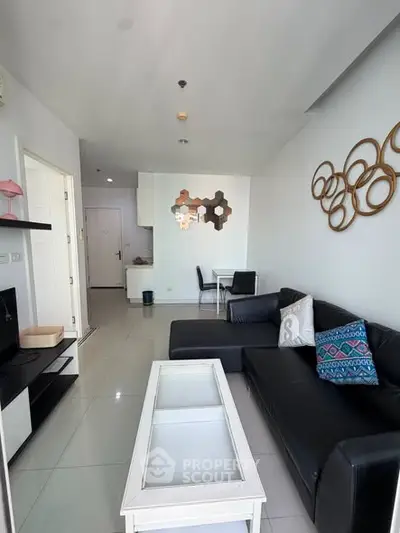 Modern living room with sleek black sofa and stylish decor in a bright apartment.