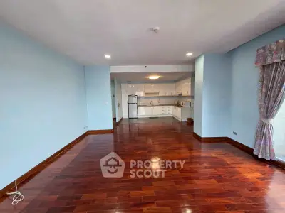 Spacious open-layout living room with hardwood floors and modern kitchen.