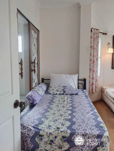 Cozy bedroom with floral bedding and curtains, classic wooden door, and a warm, inviting atmosphere perfect for relaxation.