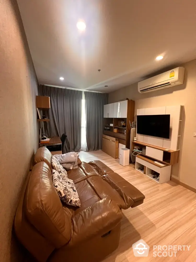 Modern living room with leather sofa and wall-mounted TV in cozy apartment