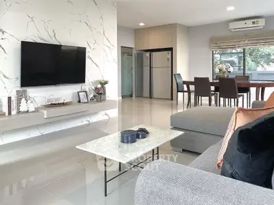 Modern living room with marble accents and open dining area, featuring sleek furniture and large windows.