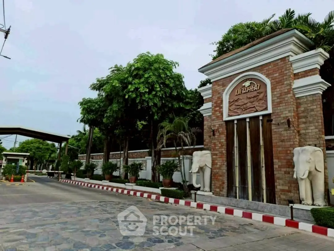 Elegant entrance of a luxury residential complex with lush greenery and decorative elements.