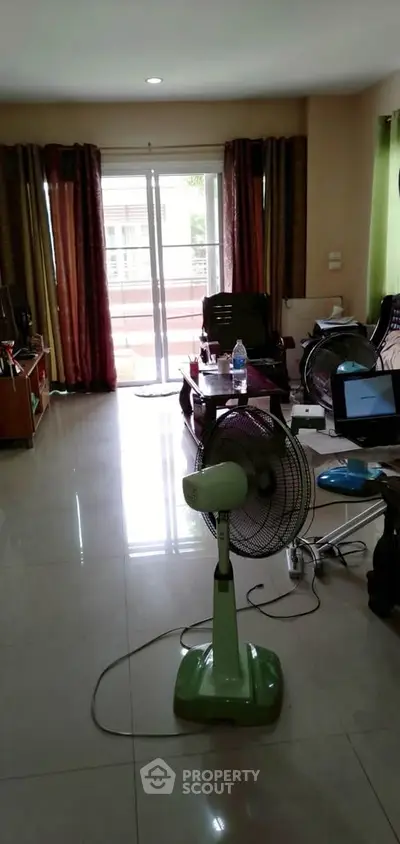 Spacious living room with sliding glass doors leading to a balcony, featuring modern furniture and natural light.