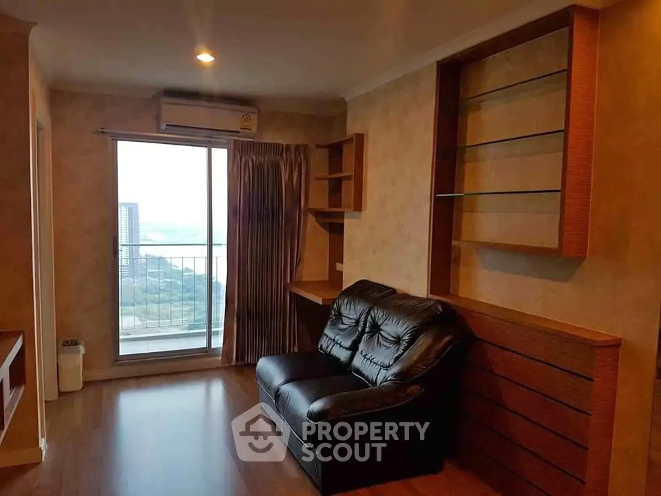 Cozy living room with a view, featuring a leather sofa and built-in shelves, perfect for relaxation.