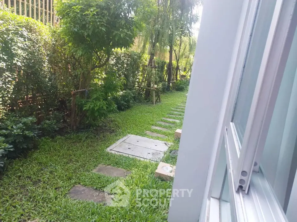 Charming garden view with lush greenery and stepping stones, perfect for outdoor relaxation.