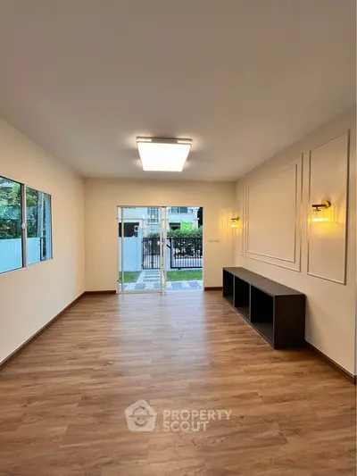 Spacious living room with wooden flooring and large windows overlooking garden.
