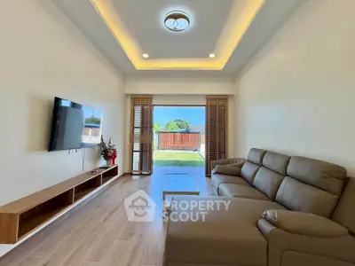 Modern living room with sleek furniture and large window offering garden view