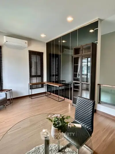 Modern living room with sleek furniture and large windows, featuring a stylish glass table and elegant decor.