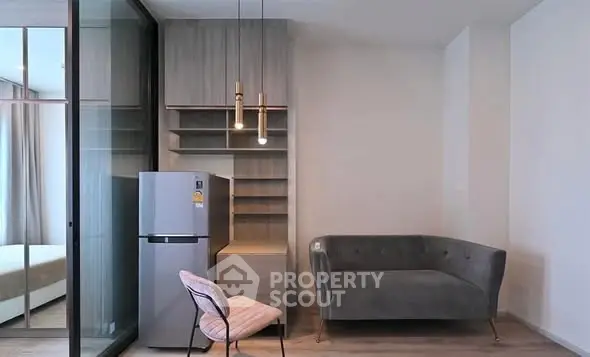Modern apartment interior with stylish sofa, chair, and refrigerator in a cozy living space.