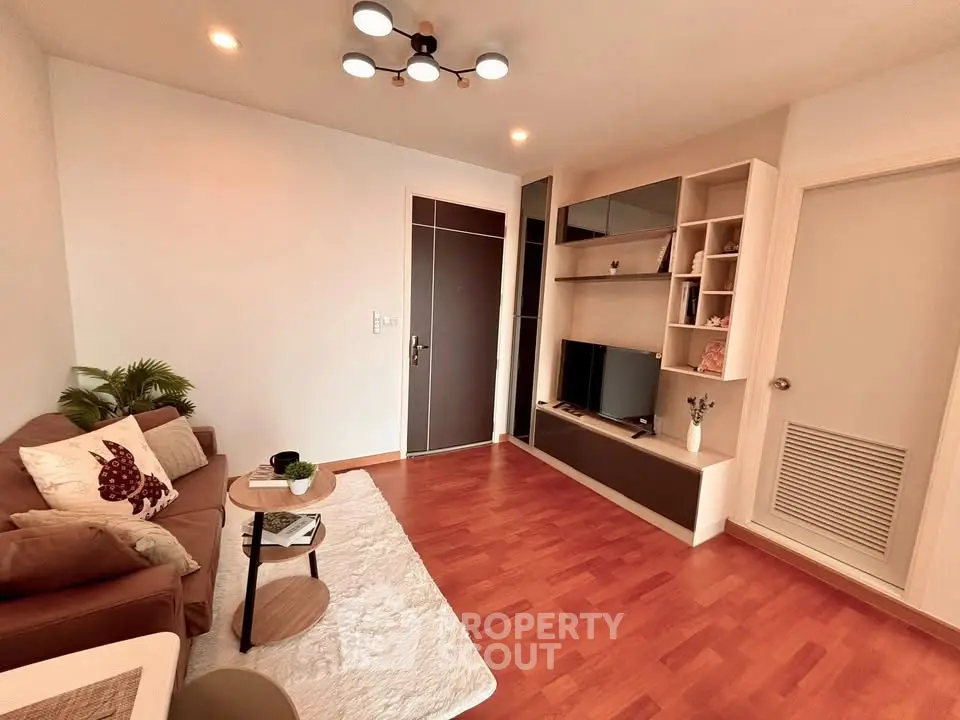 Modern living room with stylish decor and wooden flooring, featuring a cozy sofa and built-in shelving.