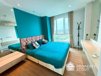 Modern bedroom with teal accents and city view, featuring stylish decor and natural light.