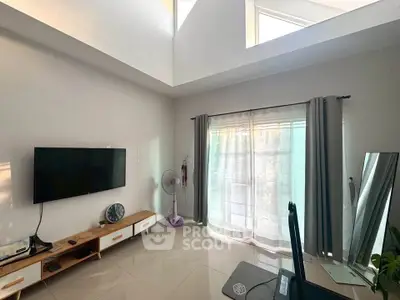Spacious living room with high ceiling and natural light, featuring modern decor and large windows.