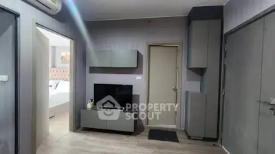 Modern apartment interior with sleek grey furniture and wall-mounted TV, showcasing a stylish and minimalist design.