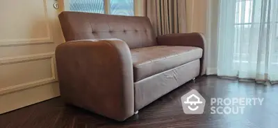 Elegant brown sofa in a stylish living room with large windows and wooden flooring.