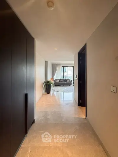 Spacious hallway leading to a modern living room with elegant decor and large windows.