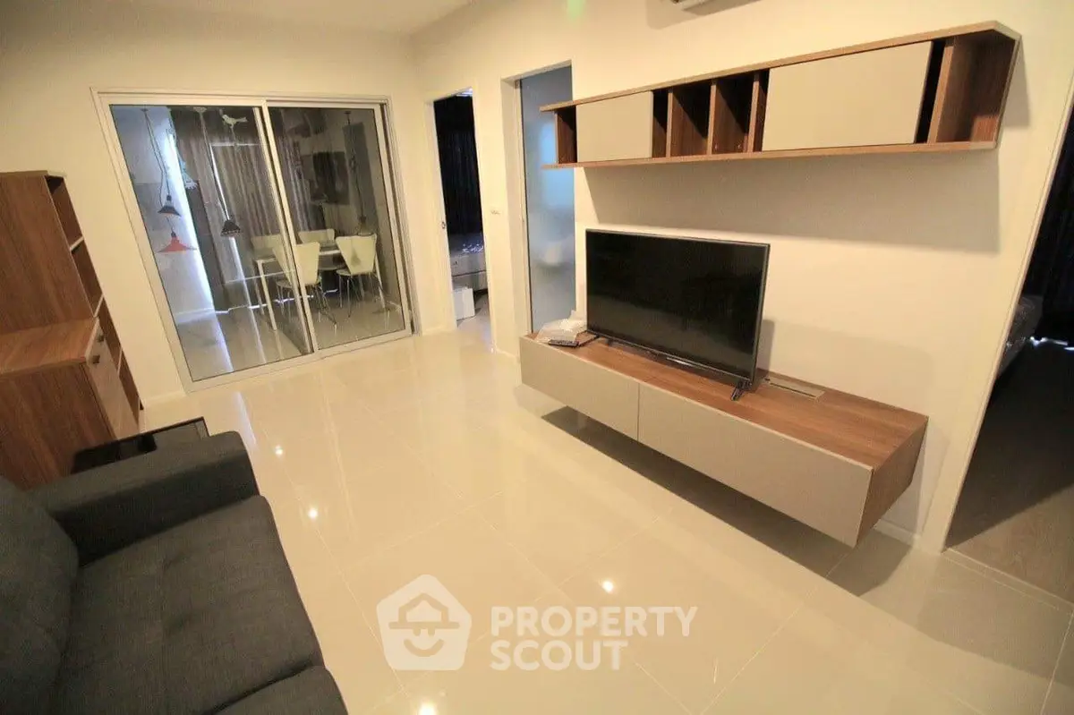 Modern living room with sleek furniture and open layout, featuring a TV and stylish shelving.