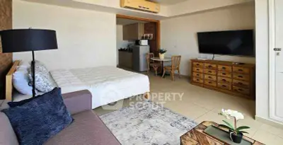 Modern studio apartment with open layout, featuring cozy bed, stylish sofa, and sleek kitchen area.