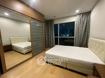 Spacious bedroom with city view, featuring a large bed and mirrored wardrobe.