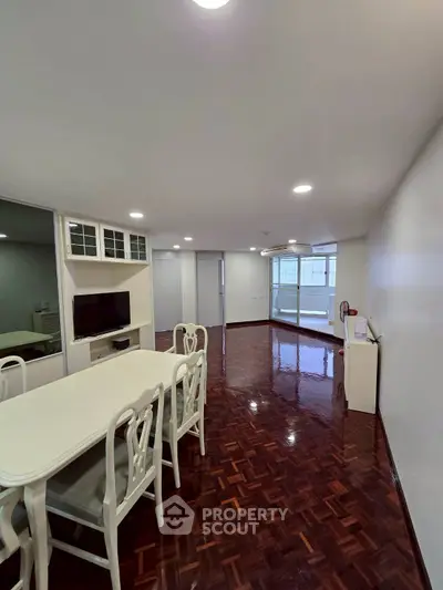 Spacious dining area with elegant white furniture and glossy wooden floors.