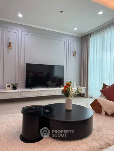 Elegant living room with modern decor and large TV, perfect for relaxation.