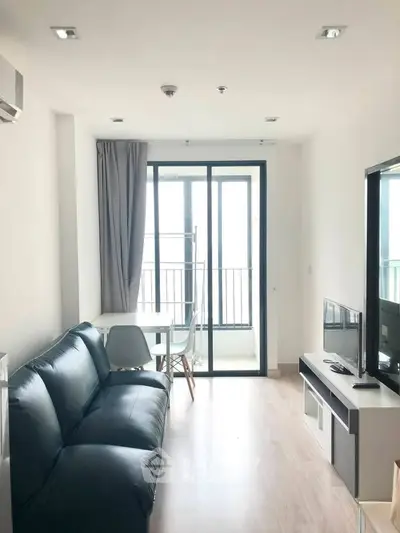 Modern living room with sleek black sofa and balcony view