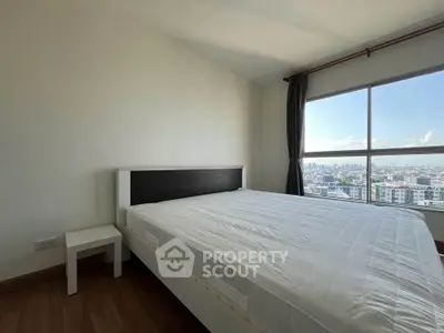 Spacious bedroom with large window offering stunning city views, perfect for relaxation and comfort.