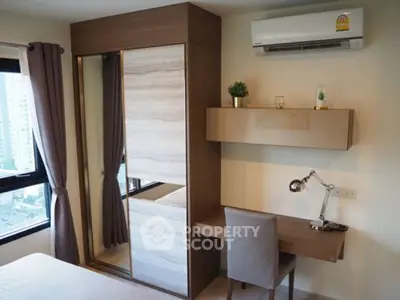 Modern bedroom with built-in wardrobe and study desk, featuring city view from window.