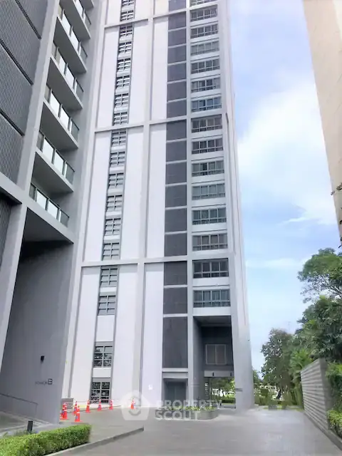 Modern high-rise building exterior with sleek design and lush greenery.