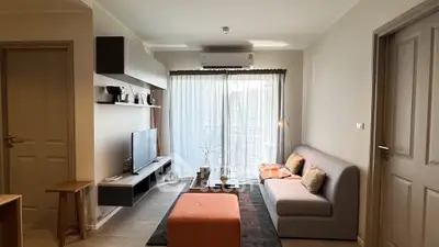Modern living room with stylish decor and natural light, featuring a cozy sofa and entertainment center.