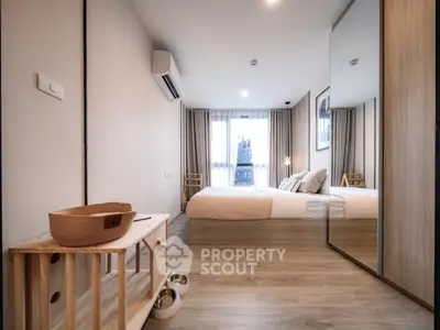Modern bedroom with stylish decor and large mirror reflecting natural light