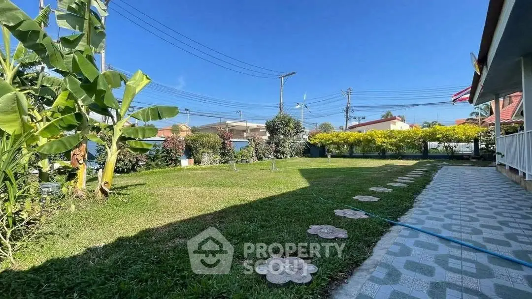 Charming garden view with lush greenery and paved walkway in a serene residential area.