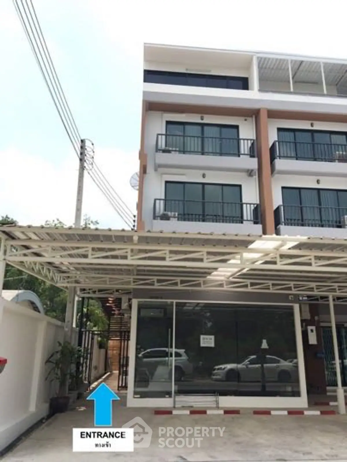 Modern multi-story building with glass facade and parking area