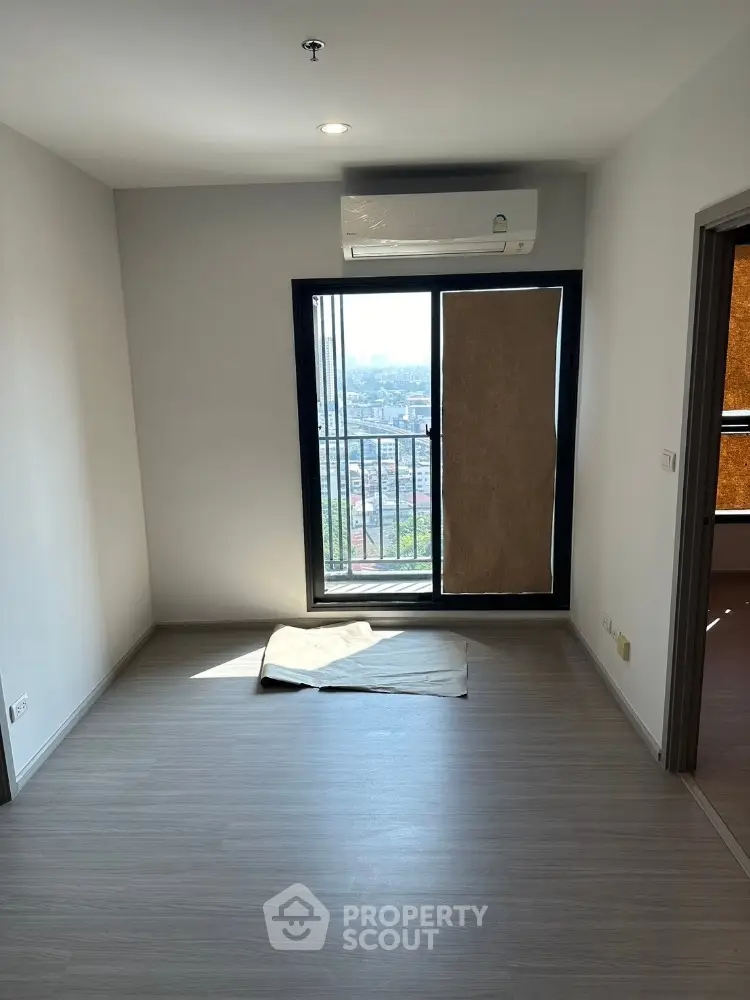 Modern apartment interior with large window and city view, featuring sleek flooring and air conditioning.
