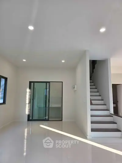 Spacious modern living room with sleek staircase and ample natural light