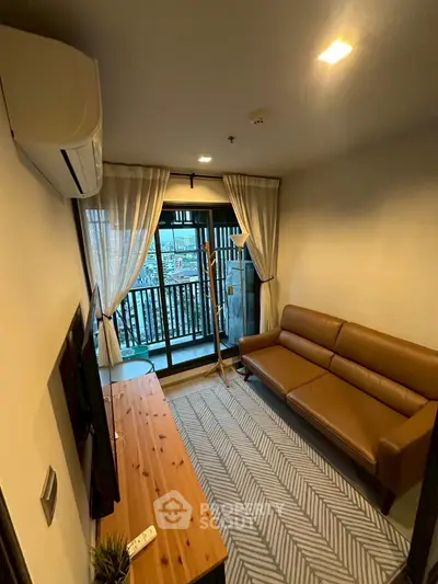 Cozy living room with leather sofa and balcony view in modern apartment.