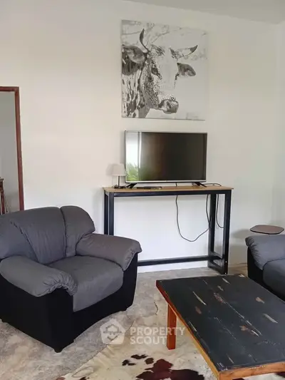Cozy living room with modern decor, featuring comfortable seating and a mounted TV, perfect for relaxation.
