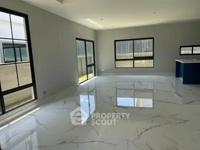 Spacious modern living room with large windows and marble flooring in a luxury home.