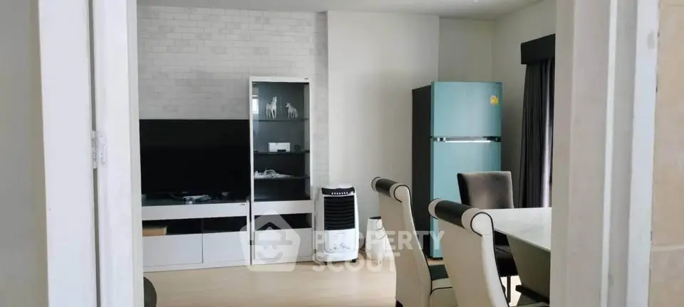 Modern living room with dining area and stylish furniture, featuring a sleek refrigerator and entertainment unit.