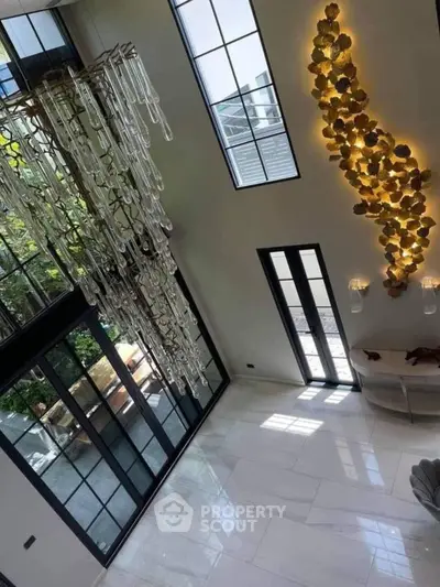 Luxurious modern living room with high ceilings, large windows, and elegant chandelier.