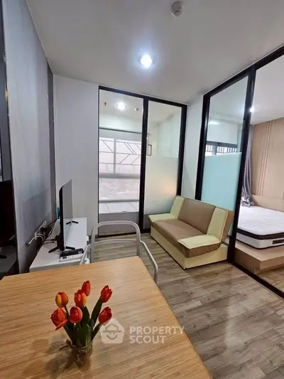 Modern apartment interior with open layout, featuring a cozy living area and bedroom with glass partition.
