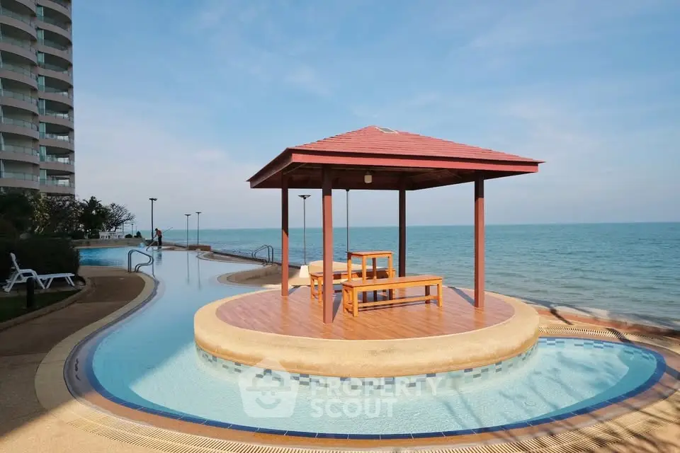Luxurious beachfront pool area with stunning ocean view and gazebo, perfect for relaxation and leisure.