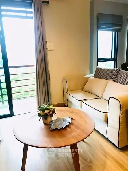 Cozy living room with natural light and balcony access, featuring a stylish sofa and wooden coffee table.