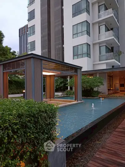Modern apartment building with elegant water feature and lush greenery